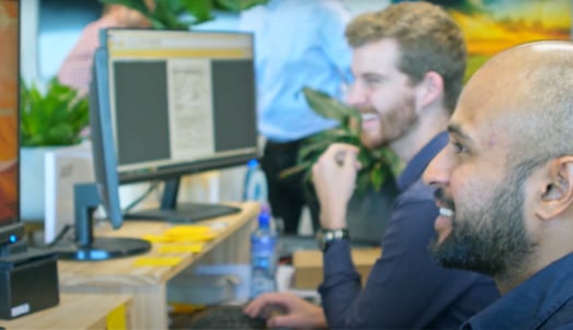 Two solar industry experts working at well-lit office desks, intensely focused on their computer tasks