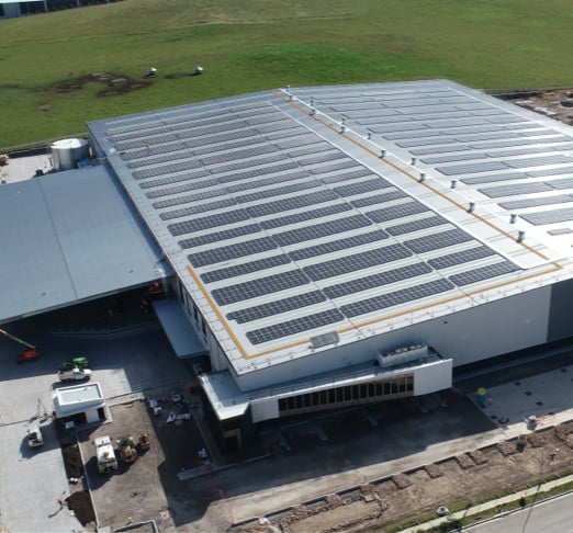 Aerial view of solar panels on a rooftop, illustrating the benefits of commercial solar investment for reducing energy costs and achieving sustainability goals