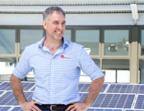 Smart Commercial Solar customer with a joyful smile posing in front of solar panels