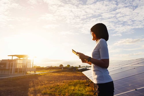 Sunset silhouette of a woman standing in front of solar panels